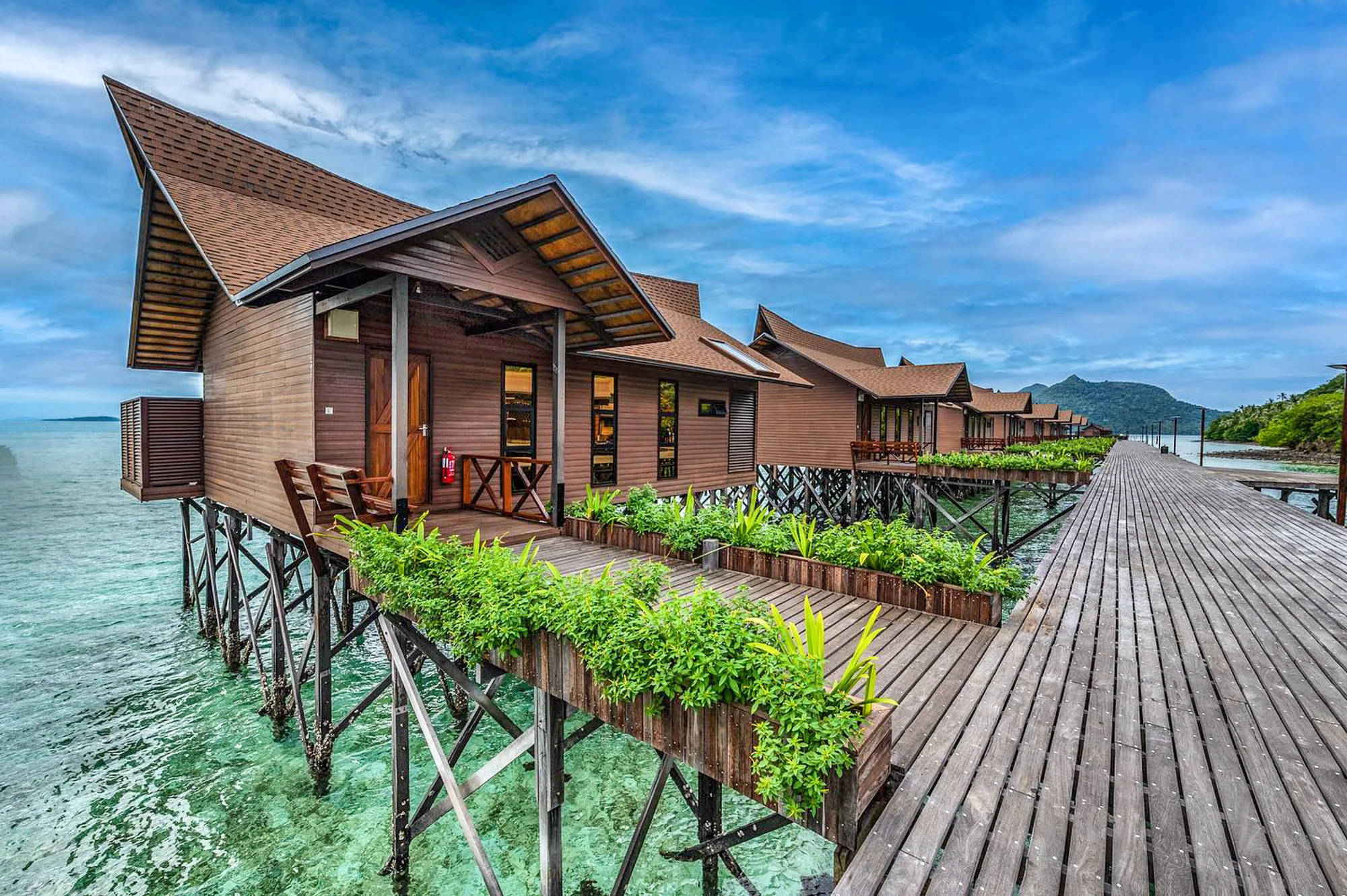 Aerial view of overwater villas at a tropical island resort on clear turquoise seas near Bohey Dulang Island, Semporna.
